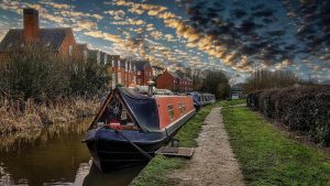 Un bateau étroit amarré sur un canal bordé d'herbe et de maisons