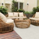 Mobilier en rotin, coussins clairs, terrasse extérieure, végétation derrière