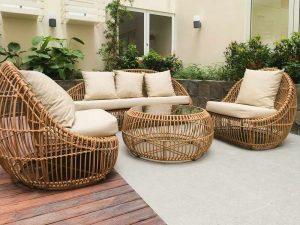Mobilier en rotin, coussins clairs, terrasse extérieure, végétation derrière